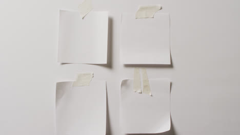 video of close up of four white memo notes with copy space taped to white background