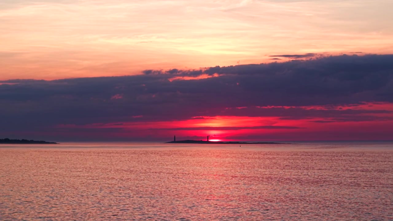 Aerial ascend reveal of sun rising behind silhouette of Thacher Island, Rockport Massachusetts