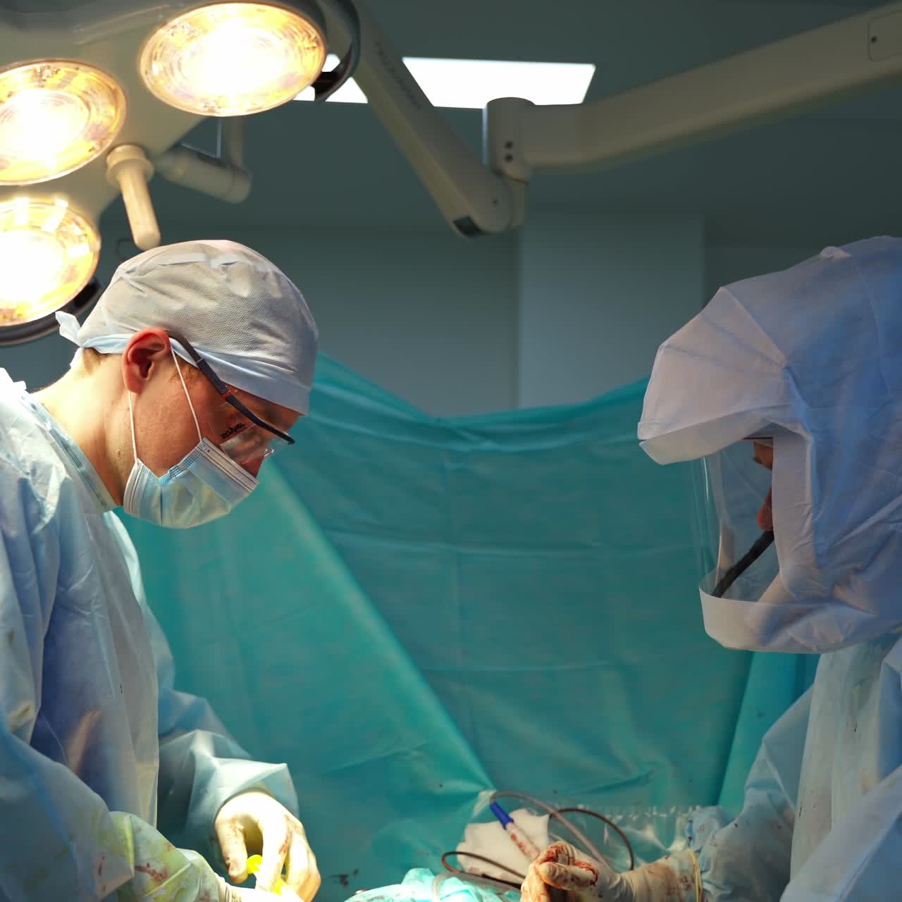 Medical workers in the hospital. Professional doctors in sterile uniform doing a surgery in the operating theater. Ending of pandemic.