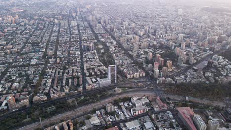 aerial dolly out of santiago city neighborhood buildings in residential area and forest park at golden hour, chile