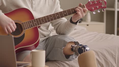 hombre con pierna protésica tocando la guitarra en casa