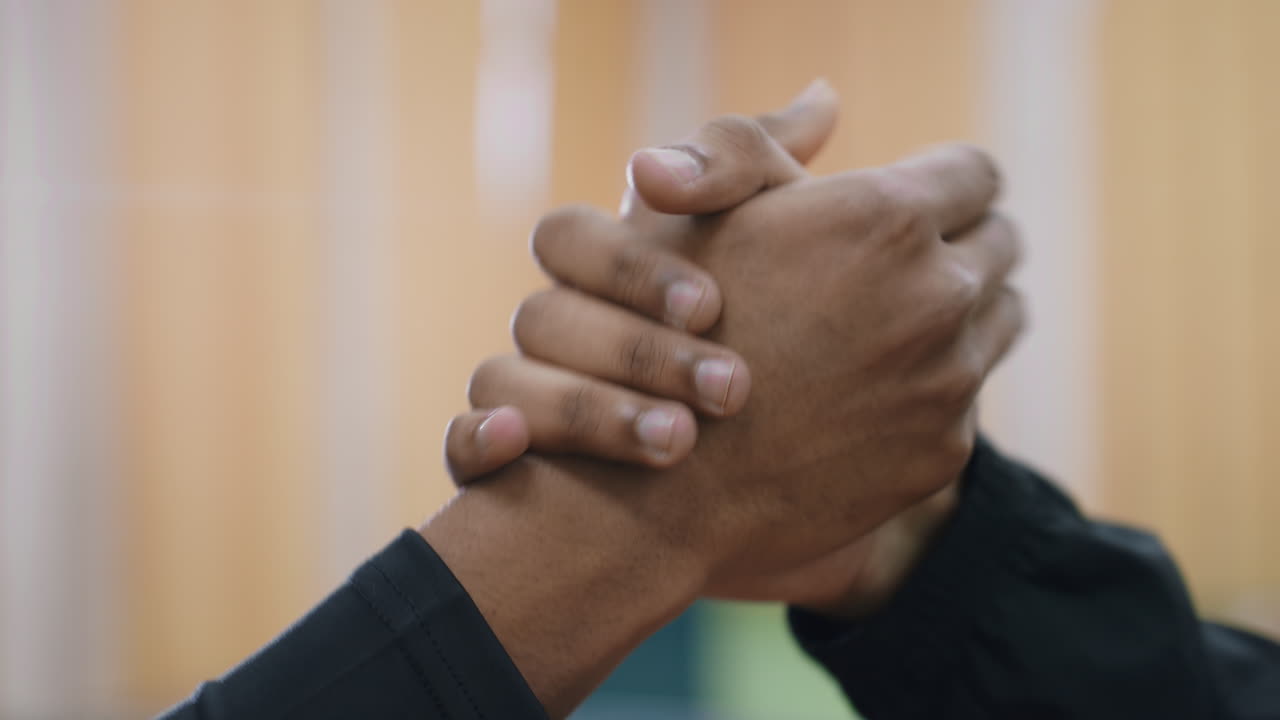 Close up hand view of two people shaking hands indoors against blurred background symbolizing respect agreement partnership connection friendship teamwork positive spirit
