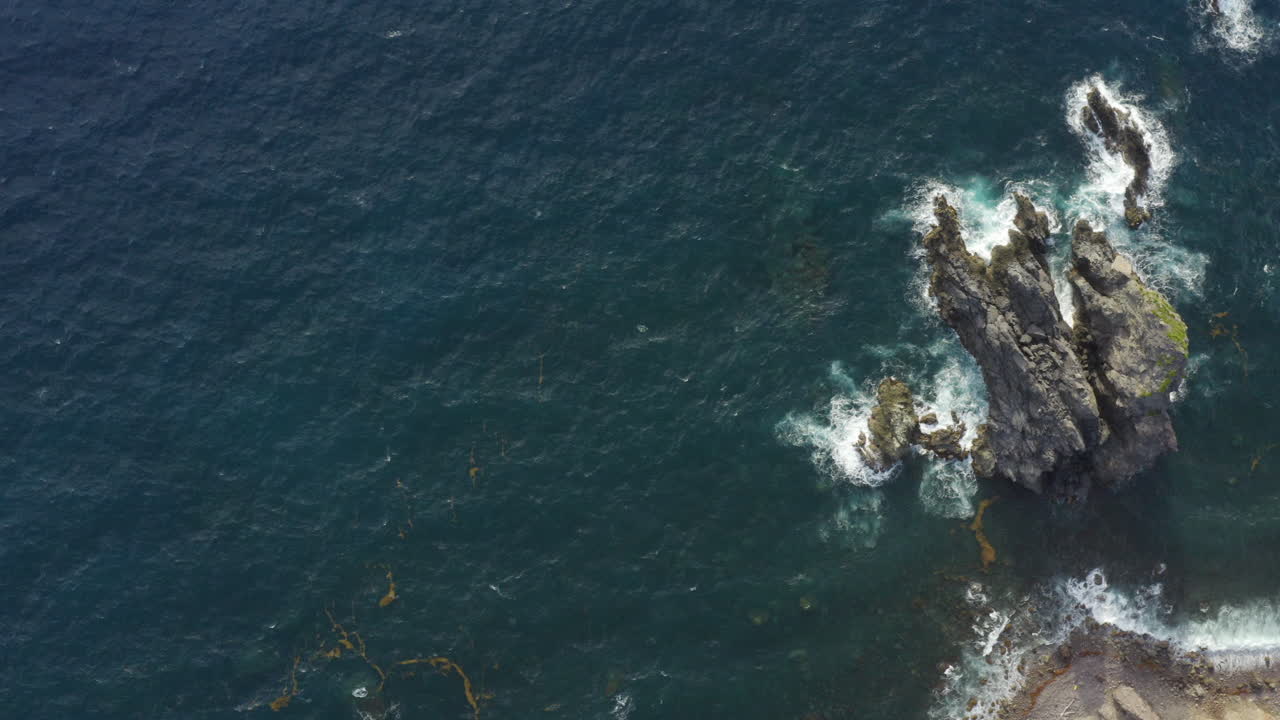 Abandoned Caribbean beach in the early morning. Plan view, smooth pan to the right, high above the blue ocean and three large rocks close to a cliff.4K UHD at 23.98 fps