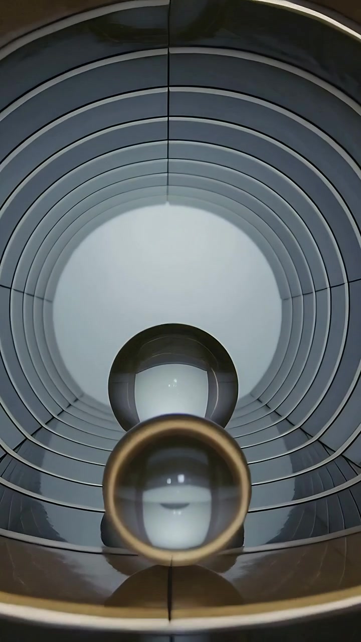 Vertical video: Rolling glass spheres moving in ribbed tunnel after tilt toward back light