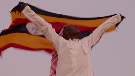 Afrikanischer-Mann-Aus-Uganda,-Der-Als-Arabischer-Staatsangehöriger-Gekleidet-Die-Flagge-Hisst