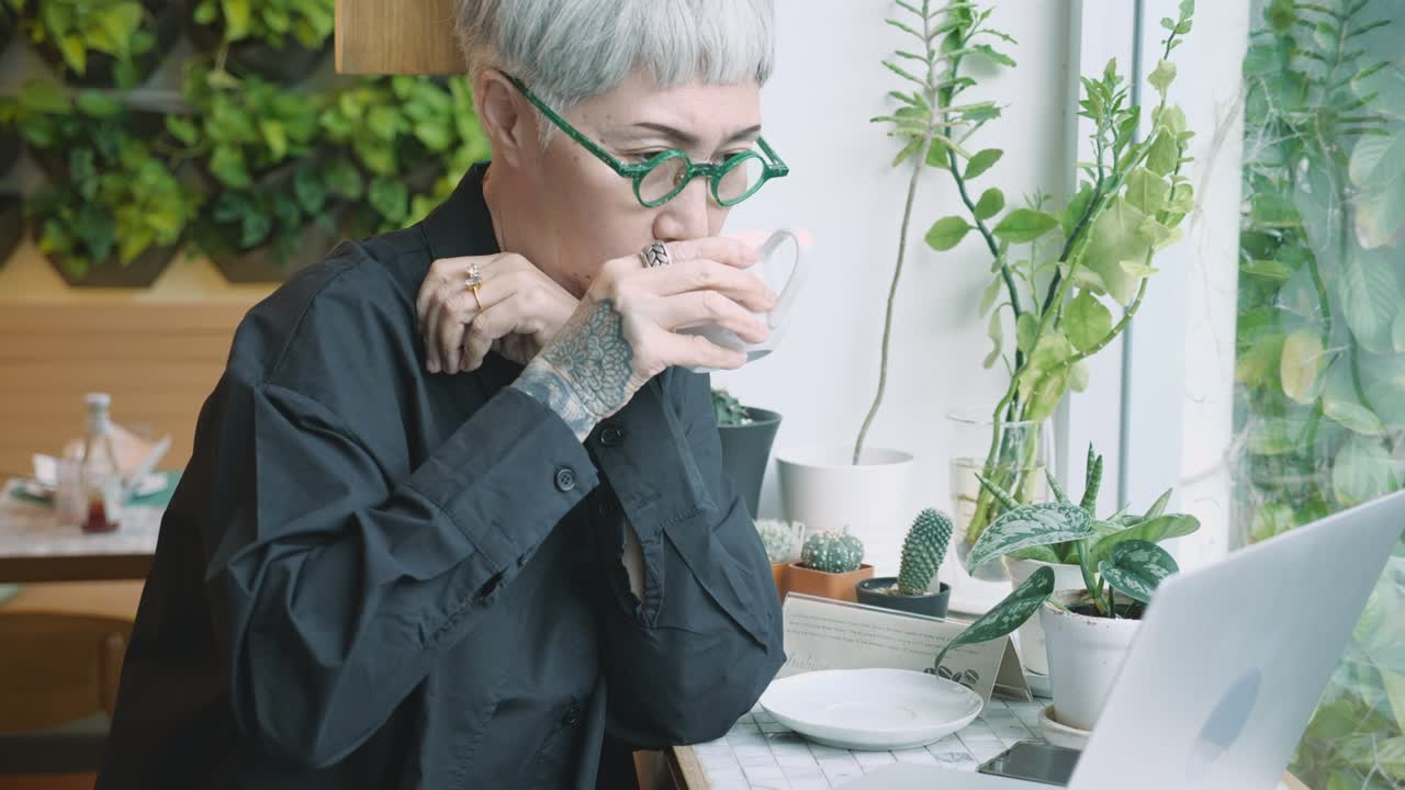 커피에서 책상 위에 노트북 컴퓨터로 일하는 아시아 여성, 노인 사업가 또는 프리랜서가 휴식을 취하기 위해 노트북을 사용하여 온라인으로 인터넷, 스타트업 비즈니스 및 커뮤니케이션 개념을 사용합니다.