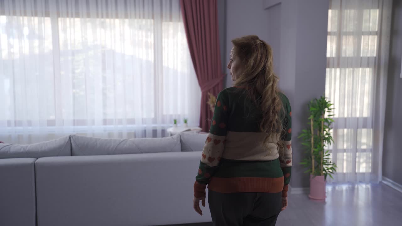 de una infeliz, triste y madura mujer mirando por la ventana de su casa, sintiéndose sola adentro.