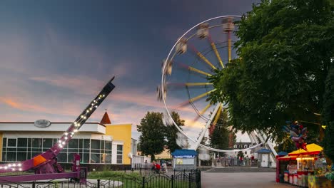 rotating in natural motion effect illuminated attraction ferris wheel on summer evening in city amusement park