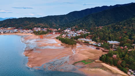picturesque sandy beach at the miyajima island, japan. aerial perspective on the iconic itsukushima shrine surrounded by multiple houses and beautiful mountains.