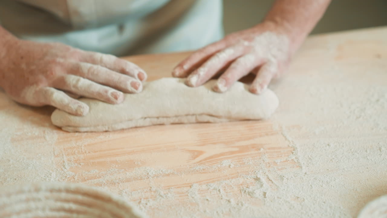 chef de panadería senior preparando masa con las manos para la baguette francesa, hombre rodando masa, haciendo pan con receta tradicional