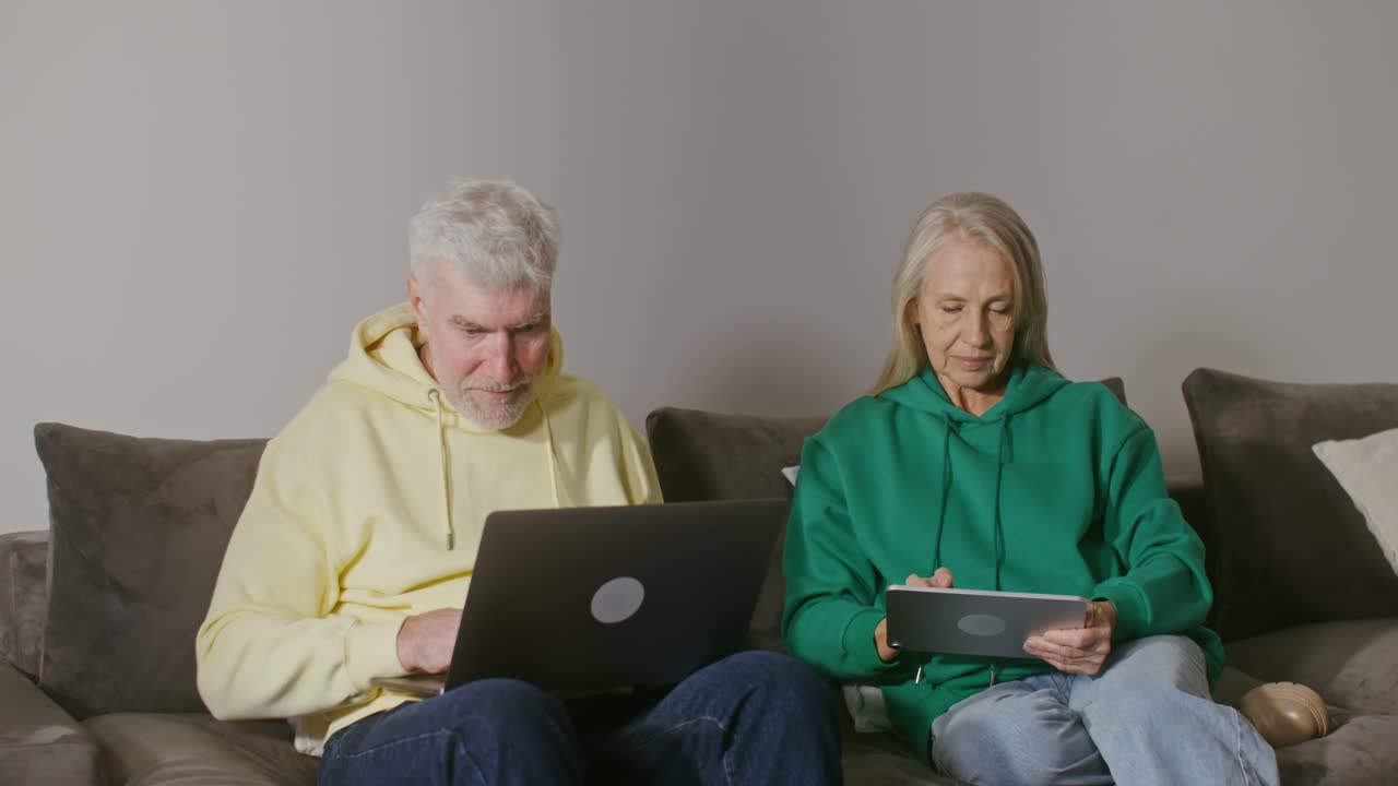 pareja de personas mayores que utilizan portátiles y tabletas