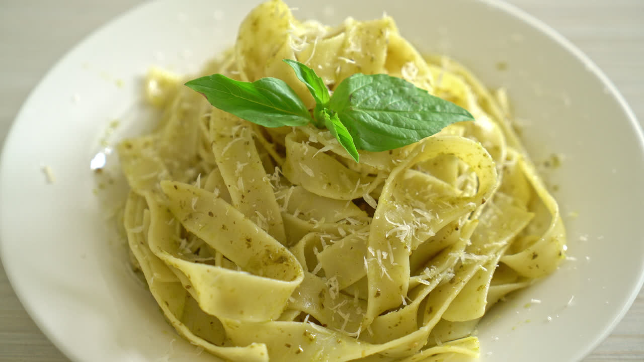 pasta fettuccine al pesto con queso parmesano encima - estilo de comida italiana
