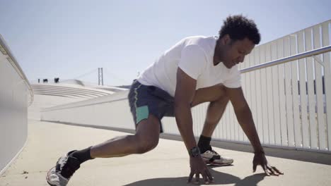 ein konzentrierter afroamerikanischer mann, der die beine auf der brücke streckt.