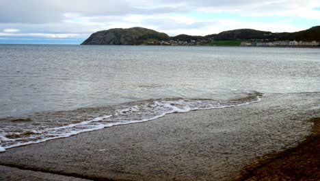 waves washing over concrete jetty landing leading to overcast ocean coastline