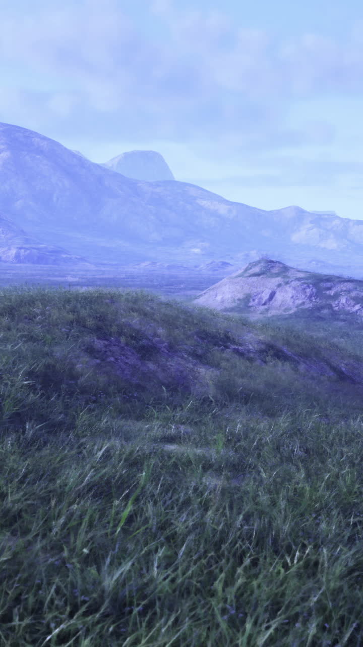 Expansive landscape with mountains and grassy terrain under a blue sky