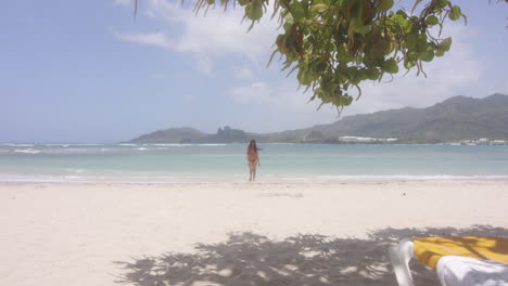 carefree latin girl walks to beach lounger from swim in turquoise blue ocean of playa teco maimon