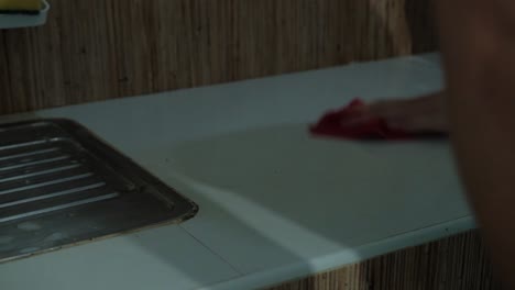 close-up shot of young man wiping down and cleaning kitchen counter with rag.