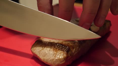 A-white-male-hand-model-is-slicing-a-lamb-meat-on-a-cutting-board-in-slow-motion