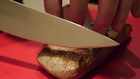 un modelo de mano masculino blanco está cortando una carne de cordero en una tabla de cortar en cámara lenta