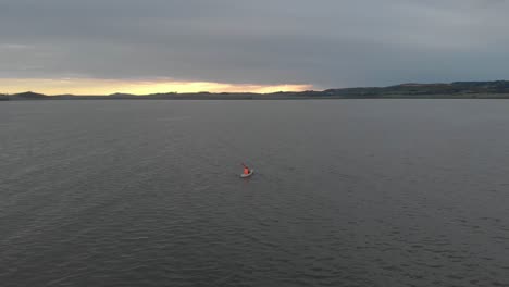 aerial orbit around with an orange life jacket kayaking on lake victoria with the sun rising on the horizon