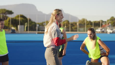 entrenadora de hockey hablando de estrategia con los jugadores