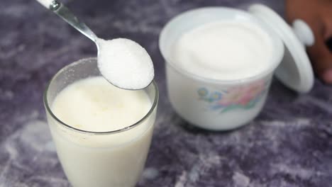 Slow-motion-of-pouring-sugar-in-a-glass-of-milk