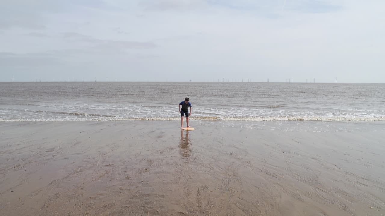 un niño en un traje de inmersión en una playa cavando en la arena