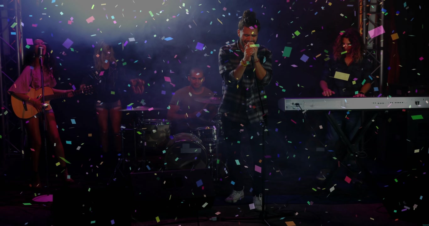 Confetti release starting as lead singer gripping mic, singing center stage while band celebrating