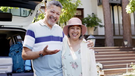 retrato de una feliz y diversa pareja de ancianos de pie junto a un coche abierto al aire libre