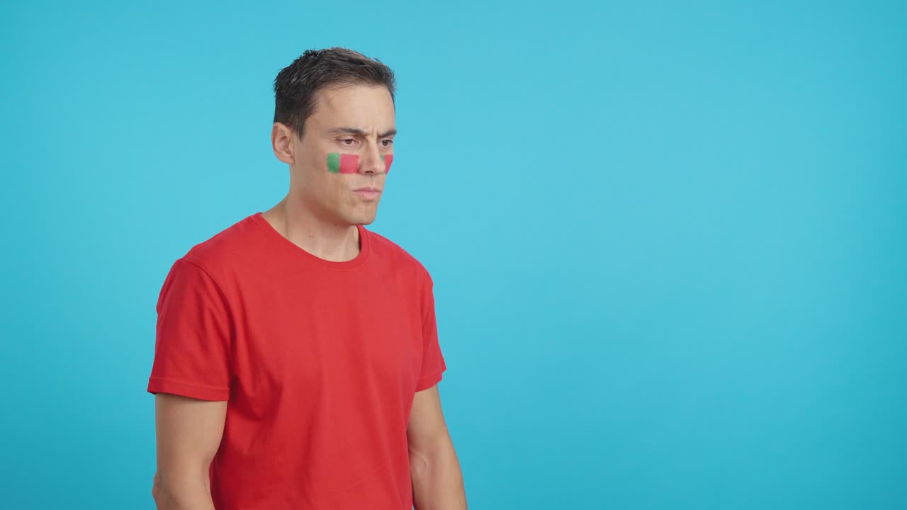 Man with portuguese flag painted looking away with serious expression