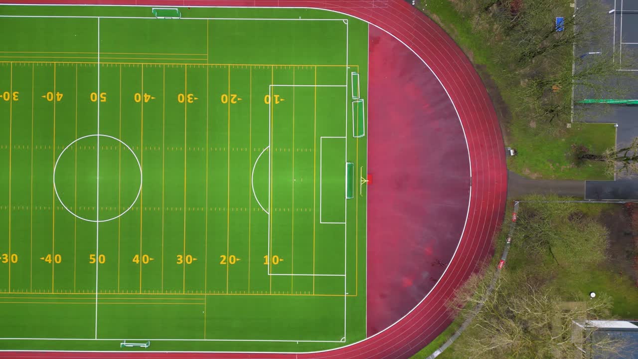 Sideways moving Drone, Birds eye view of a green and virbant football field.