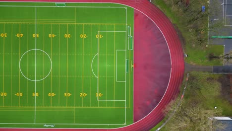 sideways moving drone, birds eye view of a green and virbant football field.