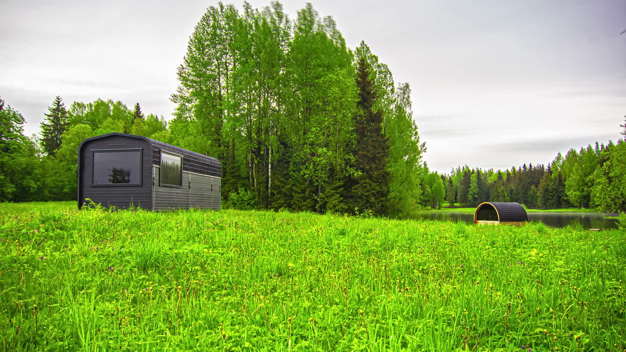 Timelapse di piccole case moderne immerse nella natura, vicino a un lago e a un bosco.