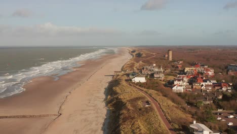 drone flying towards a touristic town in the dunes of the netherlands