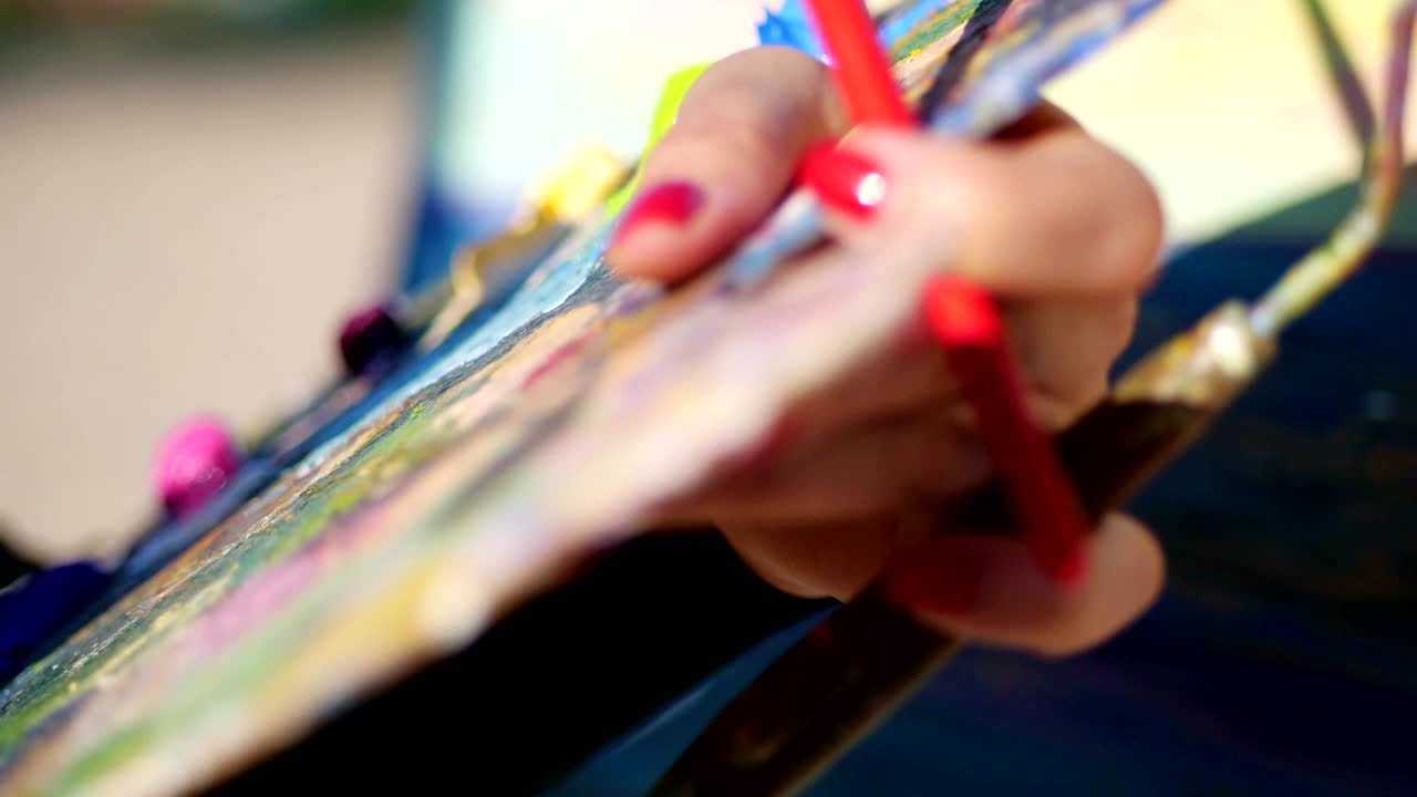 summer,outdoors, close-up of female hands of the artist and a palette with paints, the artist mixes paints with fingers on the palette. wet finger in the paint