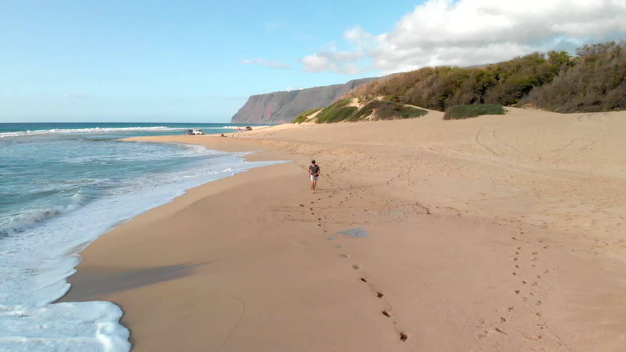 Version One. Aerial Tracking Shot of Young Man Running on Golden Secluded Beach in Hawaii.