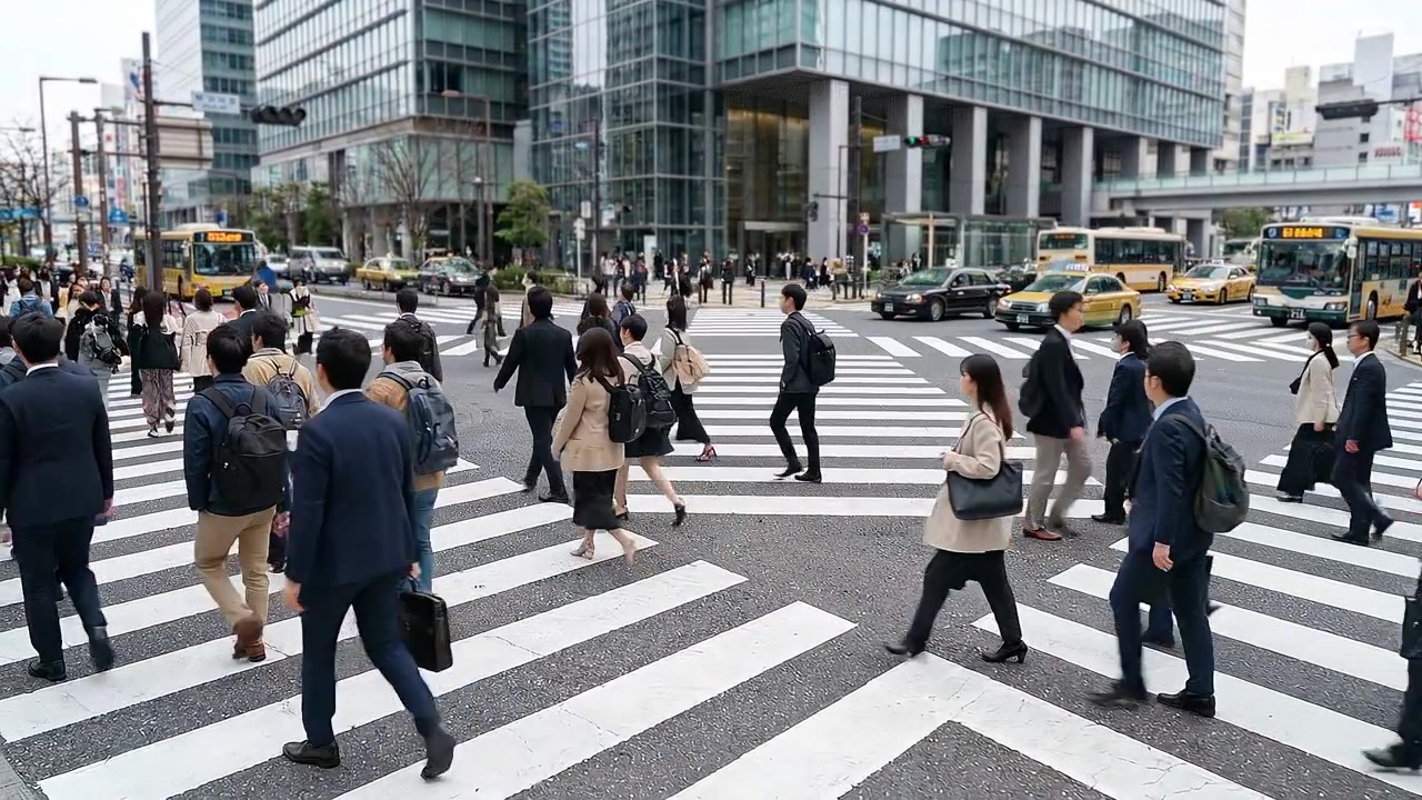 Crowd of pedestrians crossing busy city street in daytime in urban setting