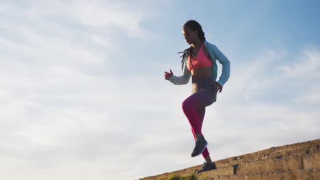 mujer afroamericana en ropa deportiva haciendo ejercicio en las escaleras en un día soleado
