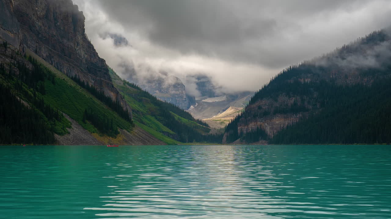Timelapse, acque turchesi incontaminate del Lago Louise e nuvole che si muovono sopra le cime del Parco Nazionale di Banff, Canada