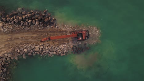 construcción de un nuevo rompeolas por máquina excavadora, vista de arriba hacia abajo
