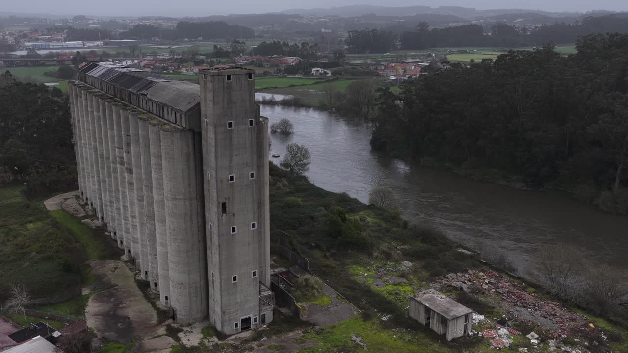 Ripresa con drone di un vecchio silo abbandonato per cereali e granaglie accanto a un fiume. Sicurezza alimentare.