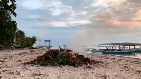 Tiro-Inclinado-Hacia-Abajo-De-La-Quema-De-Desechos-Y-Leaces-En-Una-Playa-Exótica-En-La-Isla-De-Gili-Air