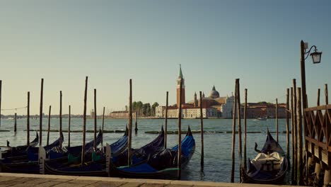 Gondolas,-typical-boats-from-Venice,-moving-on-the-water-in-the-lagoon-near-the-main-square