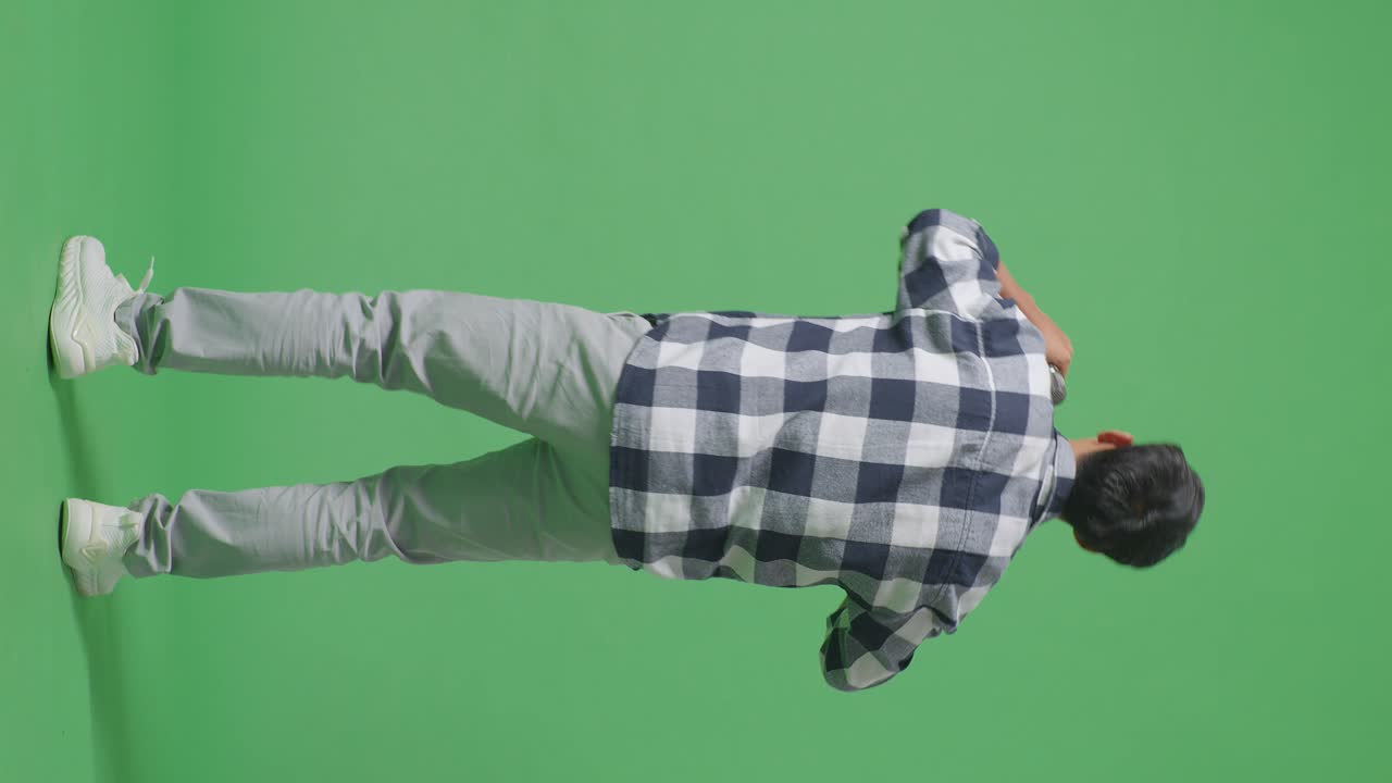 vista trasera del cuerpo completo de un joven adolescente asiático sosteniendo un micrófono y rapeando en el fondo de la pantalla verde