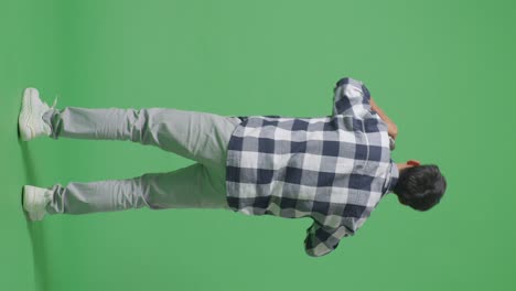 vista trasera del cuerpo completo de un joven adolescente asiático sosteniendo un micrófono y rapeando en el fondo de la pantalla verde