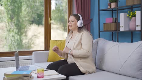 Young-woman-looking-out-the-window-and-listening-to-music-with-headphones.