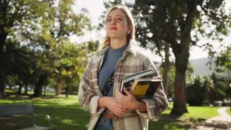 a woman holding books in a park