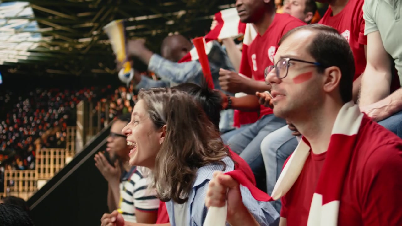 Passionate woman football supporter cheering with red team crowd