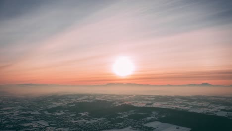 a sunset over a snow - covered forest, drone 4k