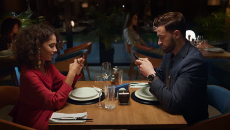 couple ordering food online at fancy restaurant table on romantic evening date.